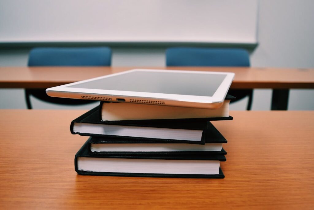 The Art of Drawing Readers In: Your attractive post title goes here A tablet rests on top of a stack of books in an empty classroom, illustrating modern education.